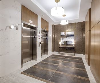 A lobby with stainless steel refrigerators and elevators and marble floors